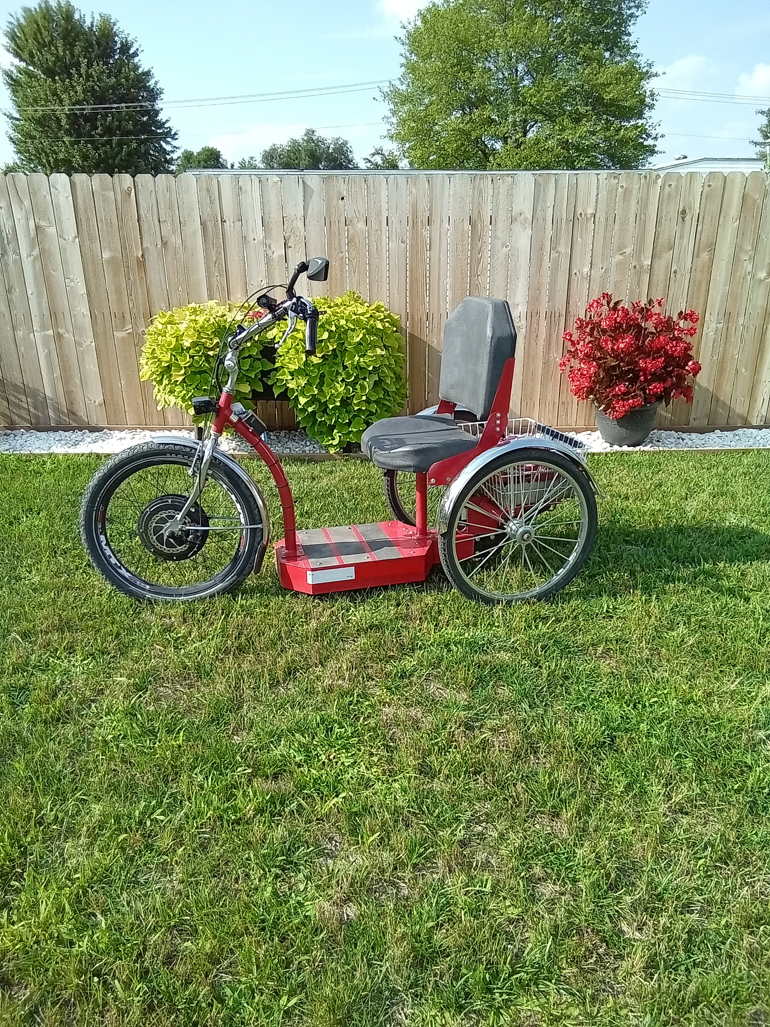 Red single-seat Step-On electric trike shown from the side